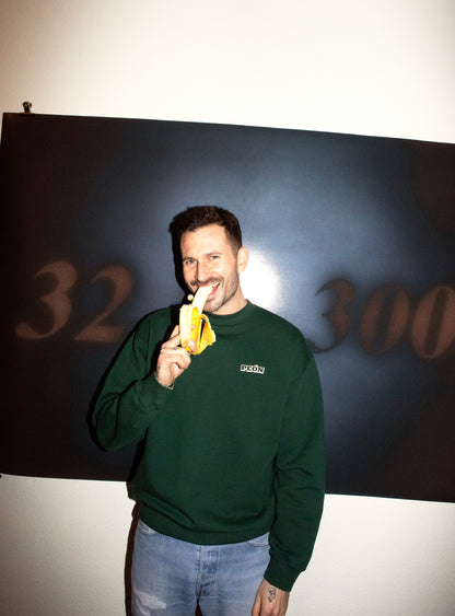 men with green sweatshirts and blue pants standing with a banana in the hand